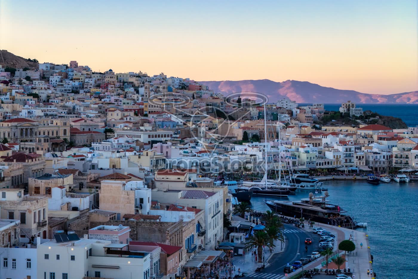 Haven van Ermoupoli op het eiland Syros met Tinos zichtbaar over de Egeïsche Zee bij zonsondergang
