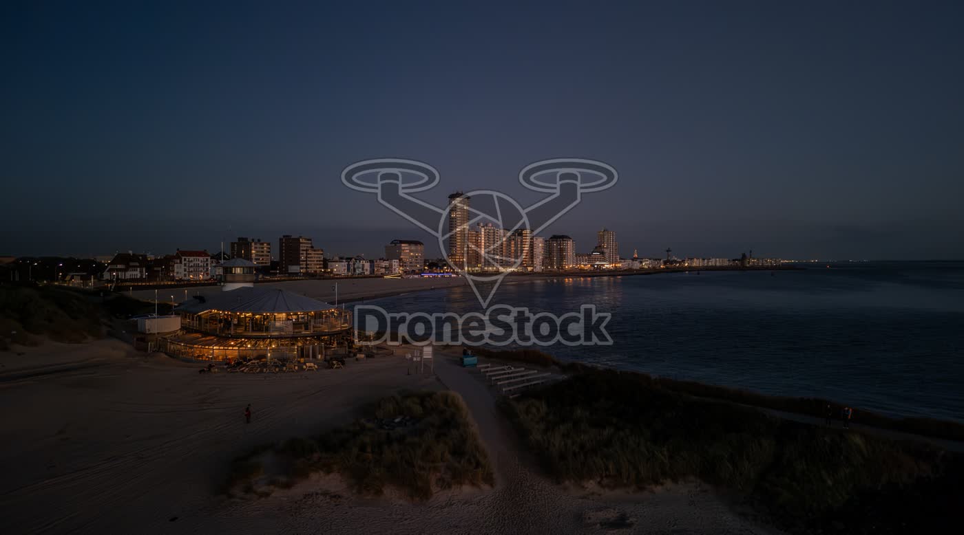 Verlicht strandpaviljoen Panta Rhei en skyline van Vlissingen bij nacht