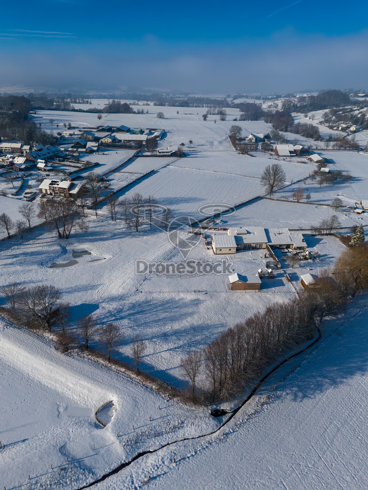 Vogelperspectief op Limburgse boerderij in een wit winterlandschap
