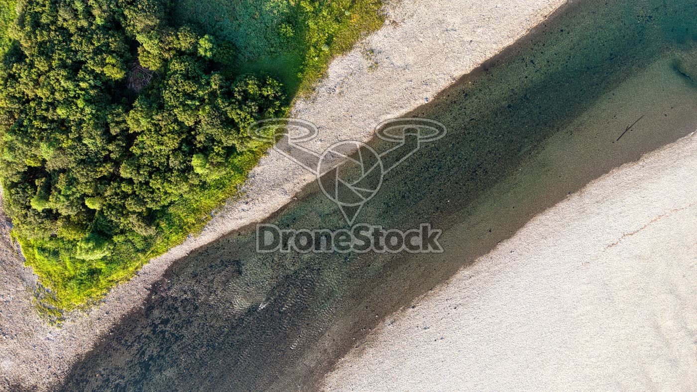 Grindbank bij rivier en bos
