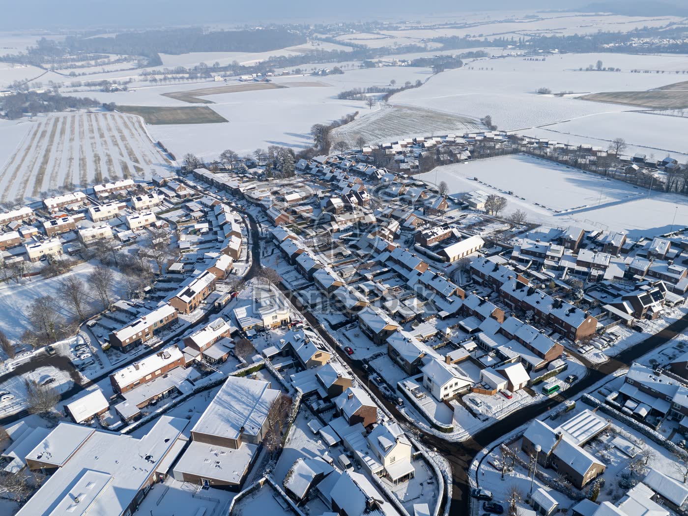Luchtfoto van besneeuwde woonwijk en velden in Vijlen