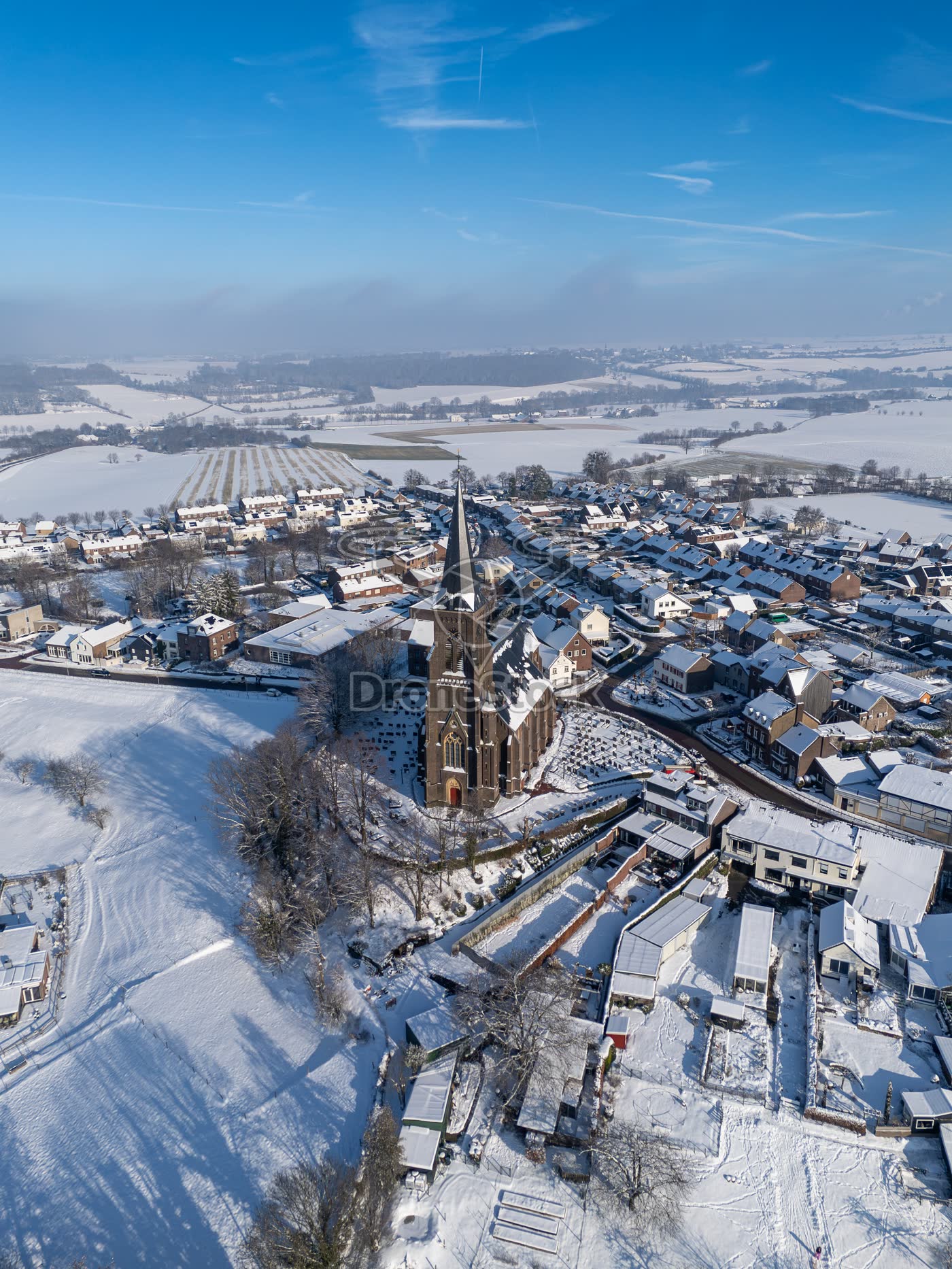 Hoge dronefoto van de Sint-Martinuskerk en besneeuwde dorpskern Vijlen