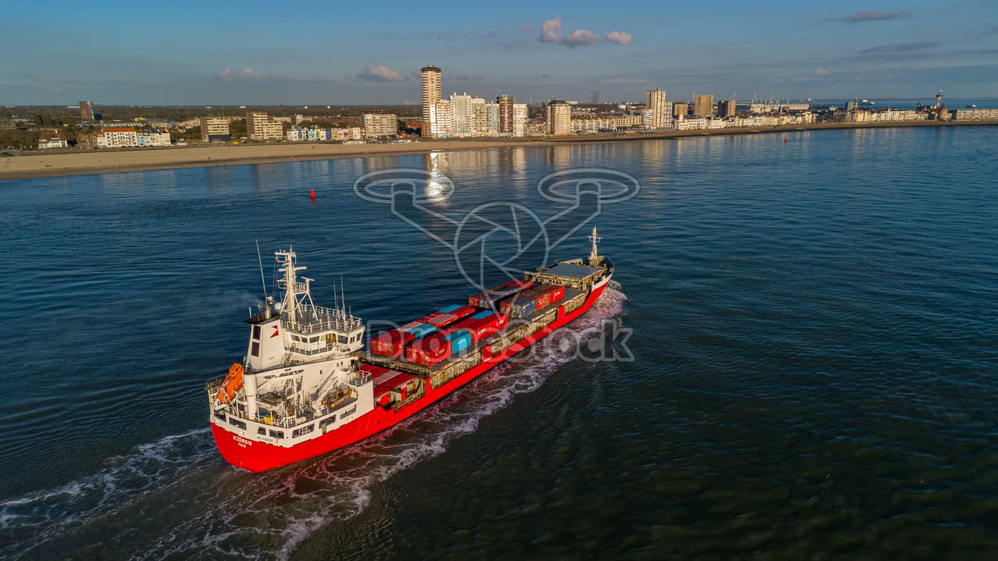Rood containerschip passeert de skyline van Vlissingen