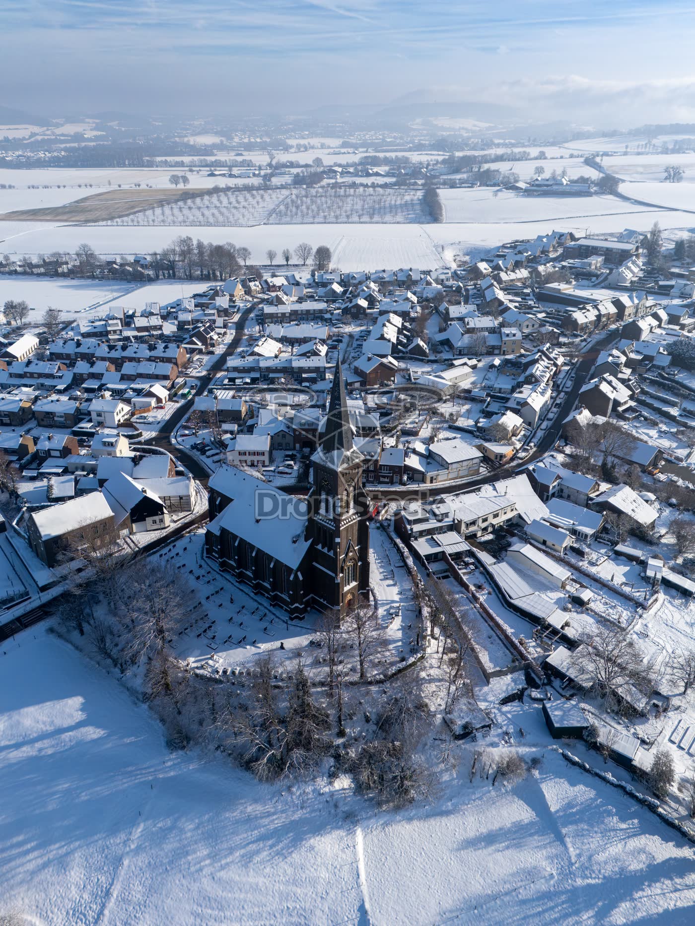 Verticale luchtopname van de Sint-Martinuskerk in Vijlen en omliggend besneeuwd heuvellandschap