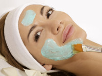 Young woman getting beauty skin mask treatment on her face with
