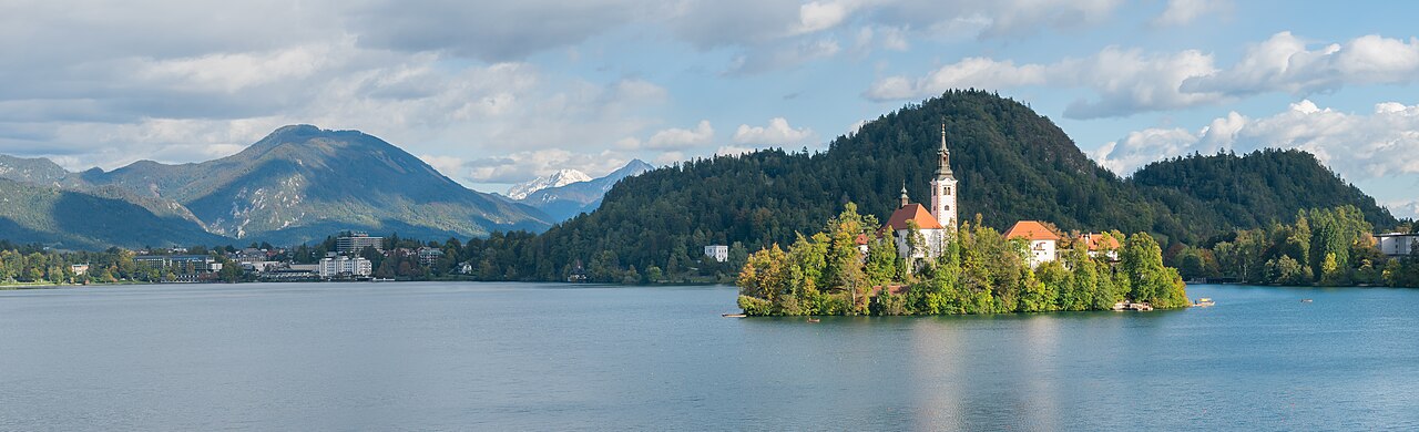 Panoramic view of Lake Bled island, Assumption of Mary Church and bell tower among green trees
