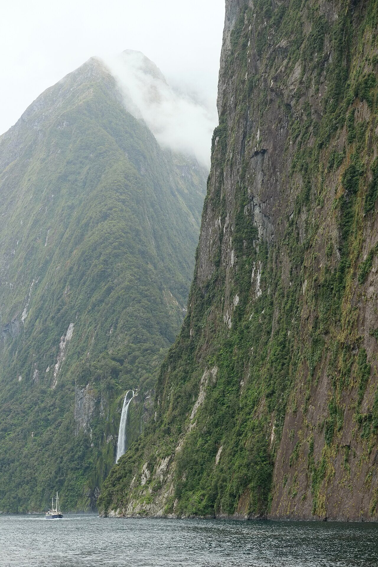 Tour boat below sheer cliff faces of Milford Sound