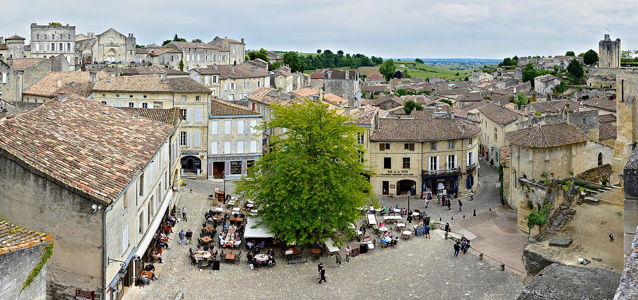 Outdoor café terrace on the village square, with vineyards stretching to the village boundary beyond the rooftops—by choosing to stay overnight, the square truly becomes yours after the evening crowd clears.