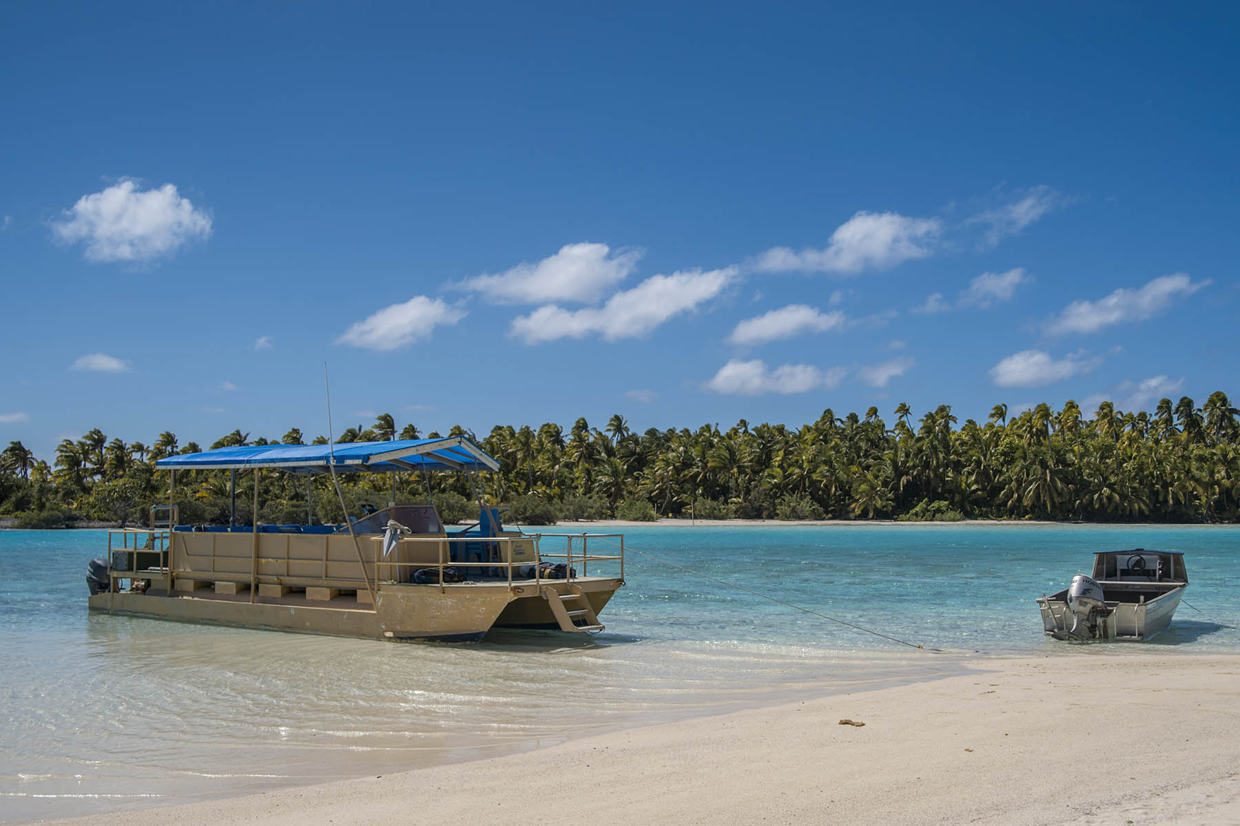 Aitutaki lagoon tour boat by white sand and shallow water