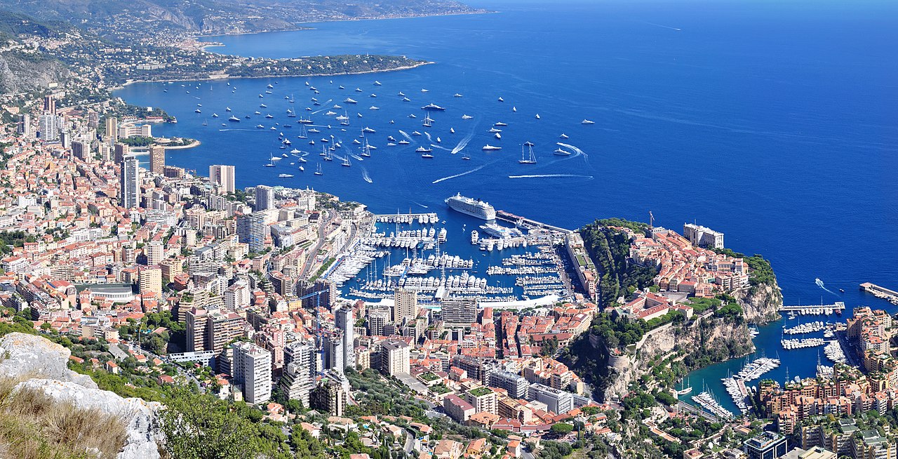 View from the heights of La Turbie overlooking Monaco and the harbor — the F1 circuit is embedded between the cliffside buildings and the yacht port