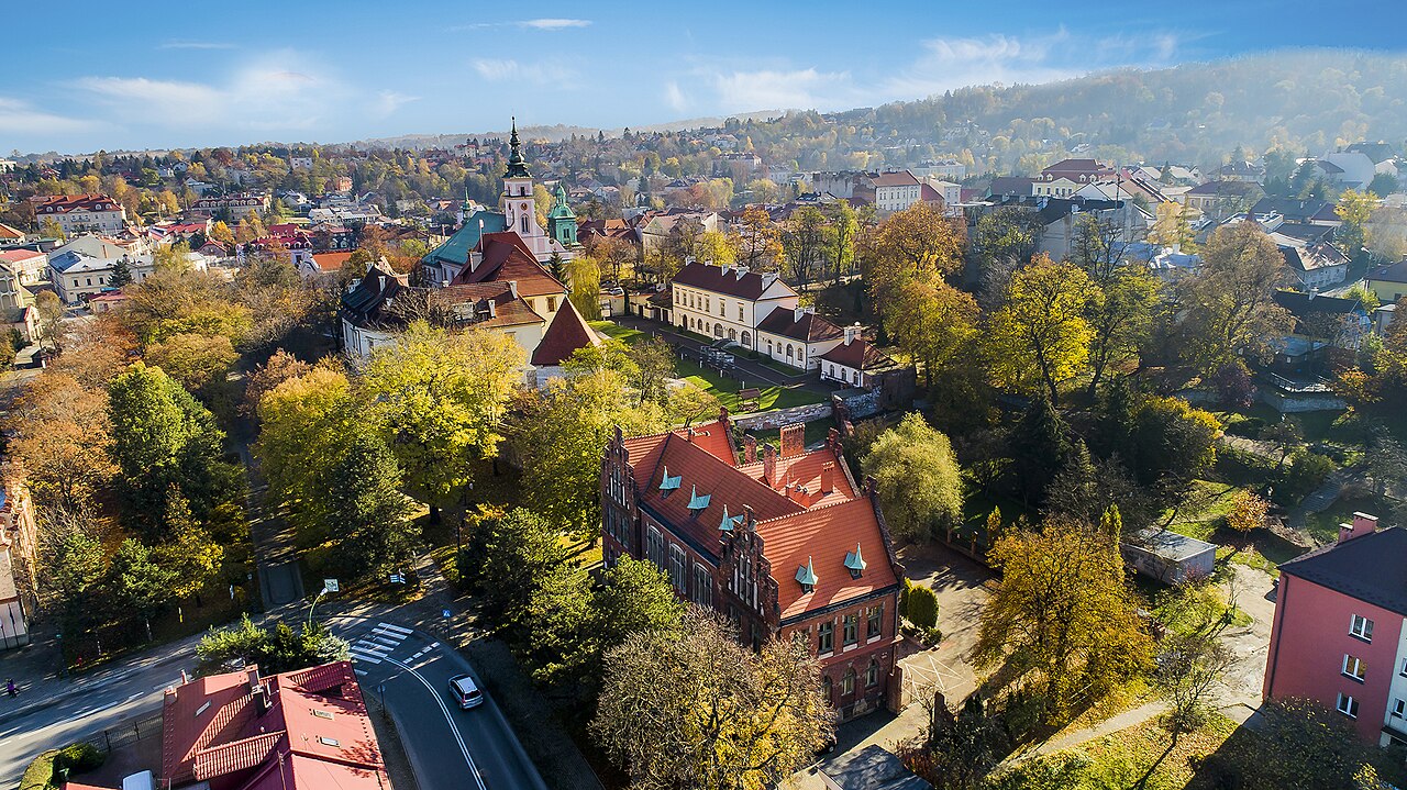 Aerial view of Wieliczka town, with red-roofed buildings and church towers amid autumn trees