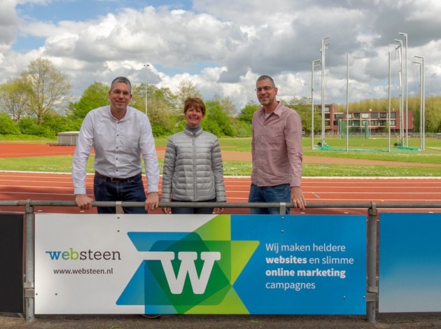 Roy en Dennis die bij een sponsorbord staan van Websteen