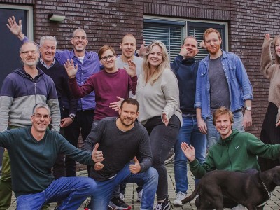 Het team van Websteen poseert voor het pand van Websteen in een gezellige sfeer
