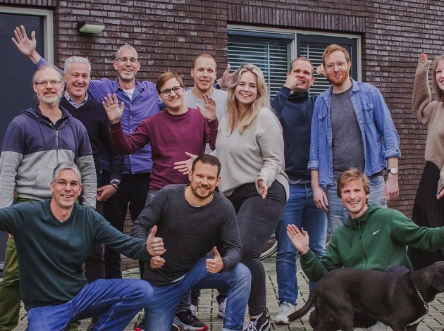 Het team van Websteen poseert voor het pand van Websteen in een gezellige sfeer