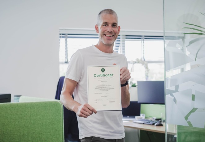 Dennis houdt het toegankelijkheids certificaat vast
