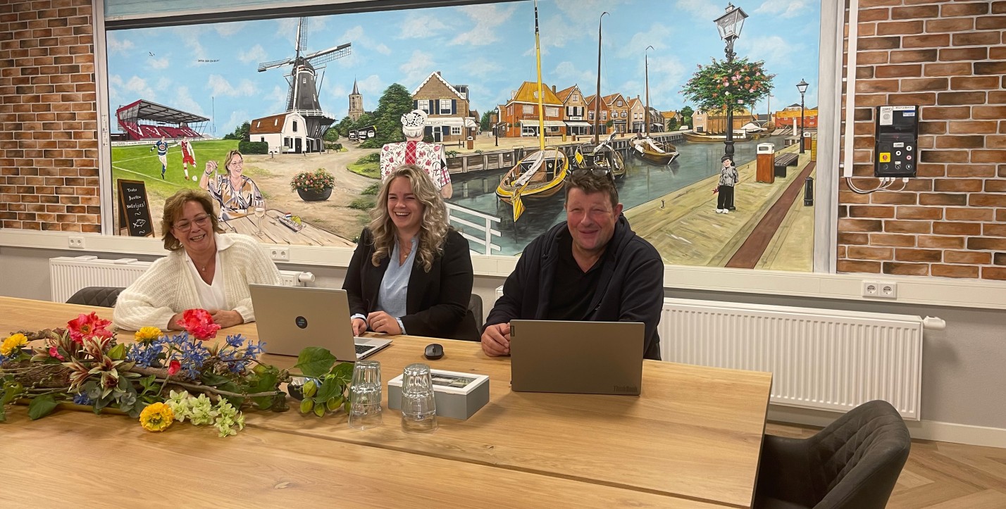 3 mensen in overleg aan een grote tafel