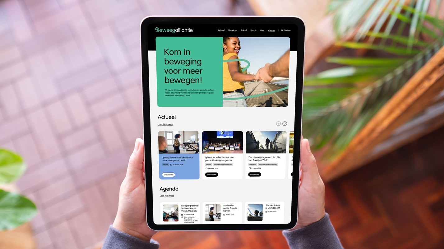 Twee handen die een tablet vasthouden waarop de website van Beweegalliantie getoond wordt