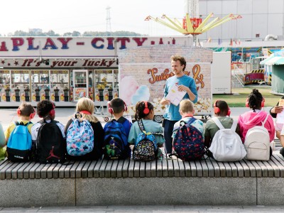 Een klas met kinderen op een bankje luisterend naar de leraar