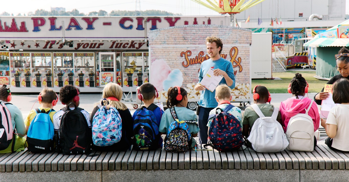 Een klas met kinderen op een bankje luisterend naar de leraar