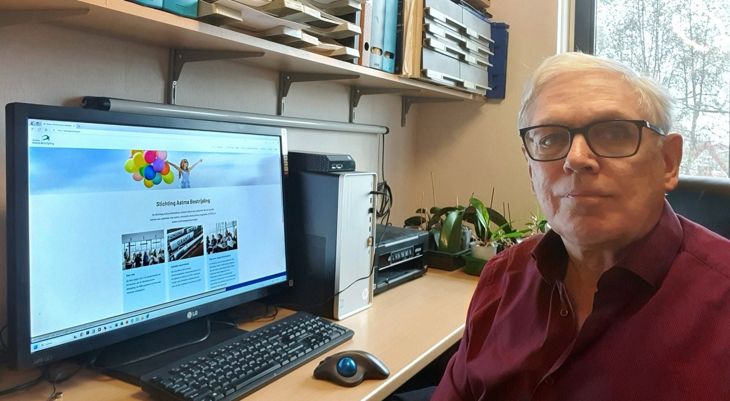 André achter het bureau met de webapplicatie van Astma Bestrijding