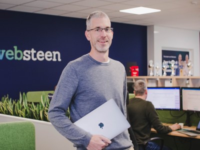 Dennis met zijn laptop in zijn hand in het kantoor van Websteen