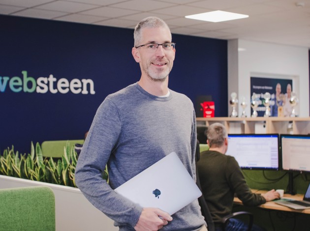 Dennis met zijn laptop in zijn hand in het kantoor van Websteen