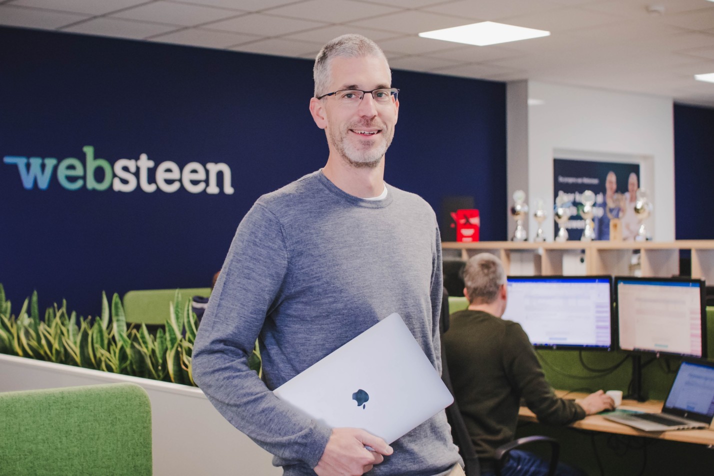 Dennis met zijn laptop in zijn hand in het kantoor van Websteen