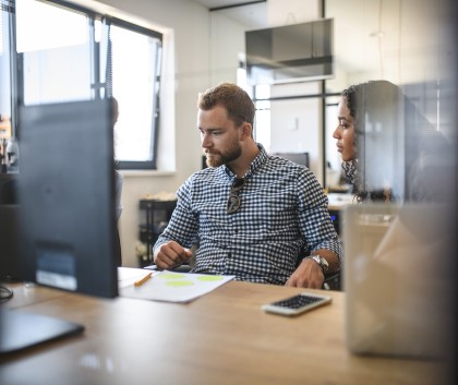 Twee medewerkers kijken samen naar computerscherm