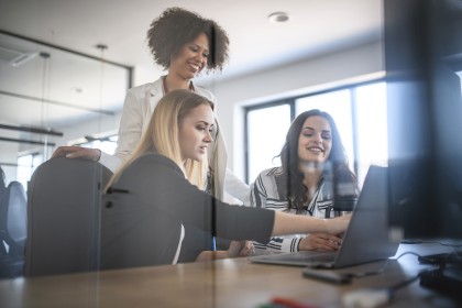 Drie medewerkers kijken samen naar computerscherm