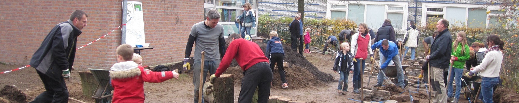 Volwassenen en kinderen die helpen bouwen aan een groen schoolplein.