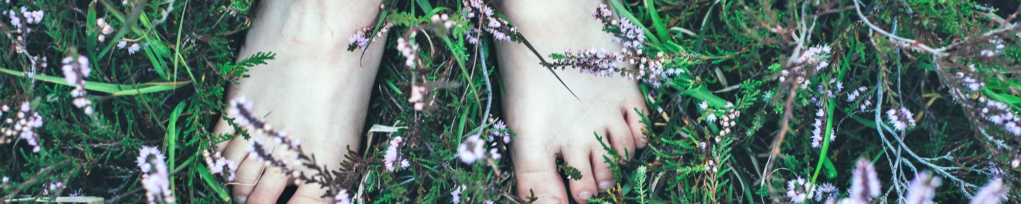 Blote voeten tussen wilde plantjes.