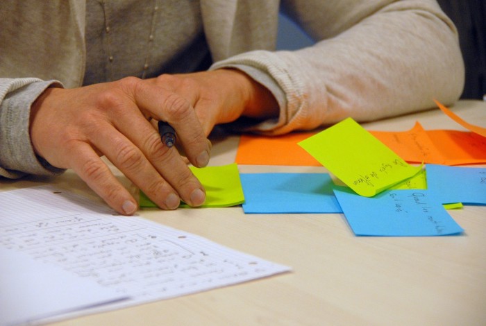 Een persoon zit aan een tafel die is volgeplakt met post-its