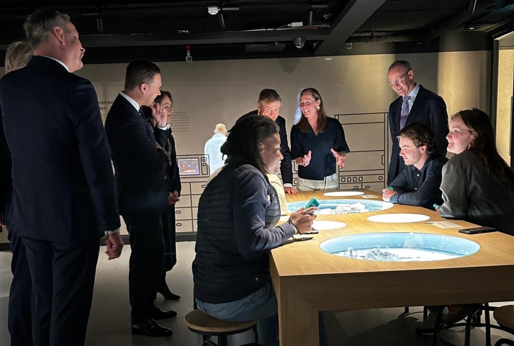 Tijdens de opening van De Nederlandsche Bank geeft Stefanie uitleg over een tentoonstellingselement  aan Koning Willem-Alexander, Klaas Knot, Eelco Heinen, Martin van Rijn en Femke halsema