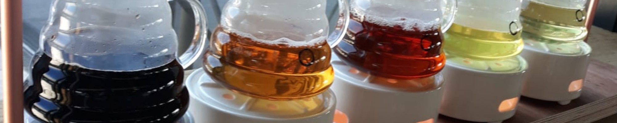 Close up van glazen potten met verschillende soorten thee. Ze staan gesorteerd van licht naar donker.