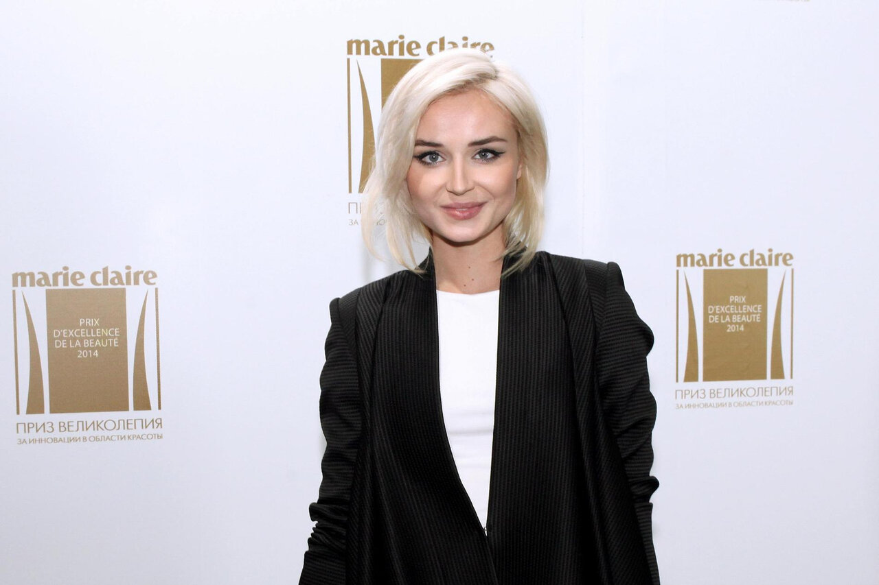 Полина Гагарина на сцене во время корпоративного мероприятия, рядом стоит диван.