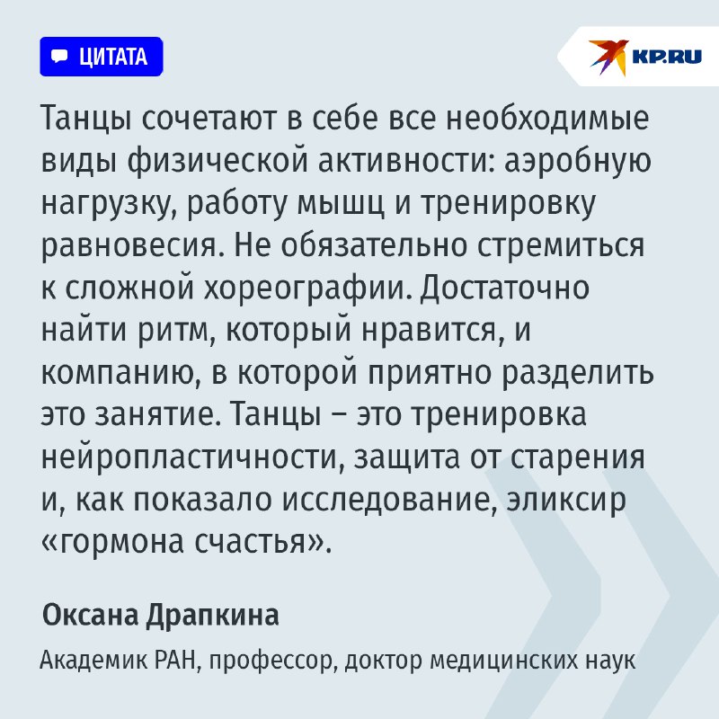Женщина средних лет с улыбкой танцует на кухне, рядом стоят фрукты и овощи