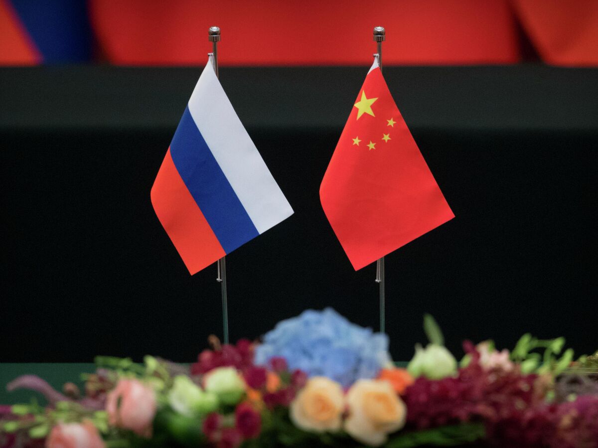 Логотипы России и Китая, соединенные технологическими линиями, на фоне футуристического городского пейзажа Шэньчжэня