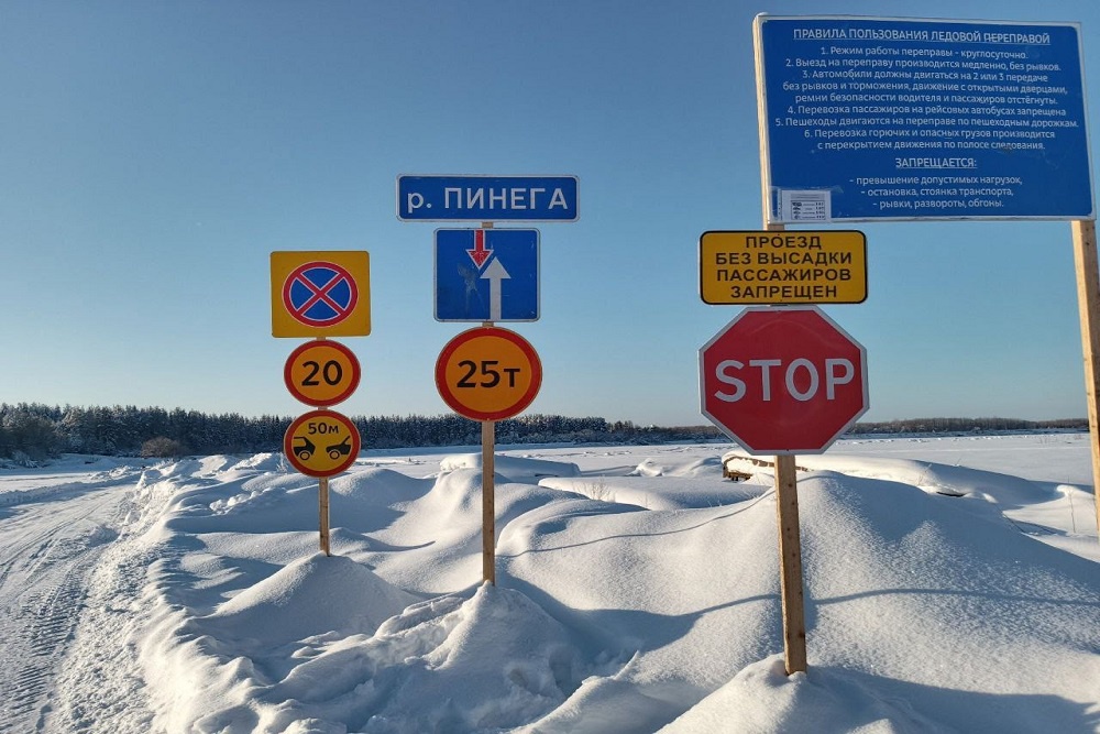 Зимняя дорога, построенная изо льда, по которой движутся грузовики. На обочине видны заснеженные деревья и суровый северный пейзаж.