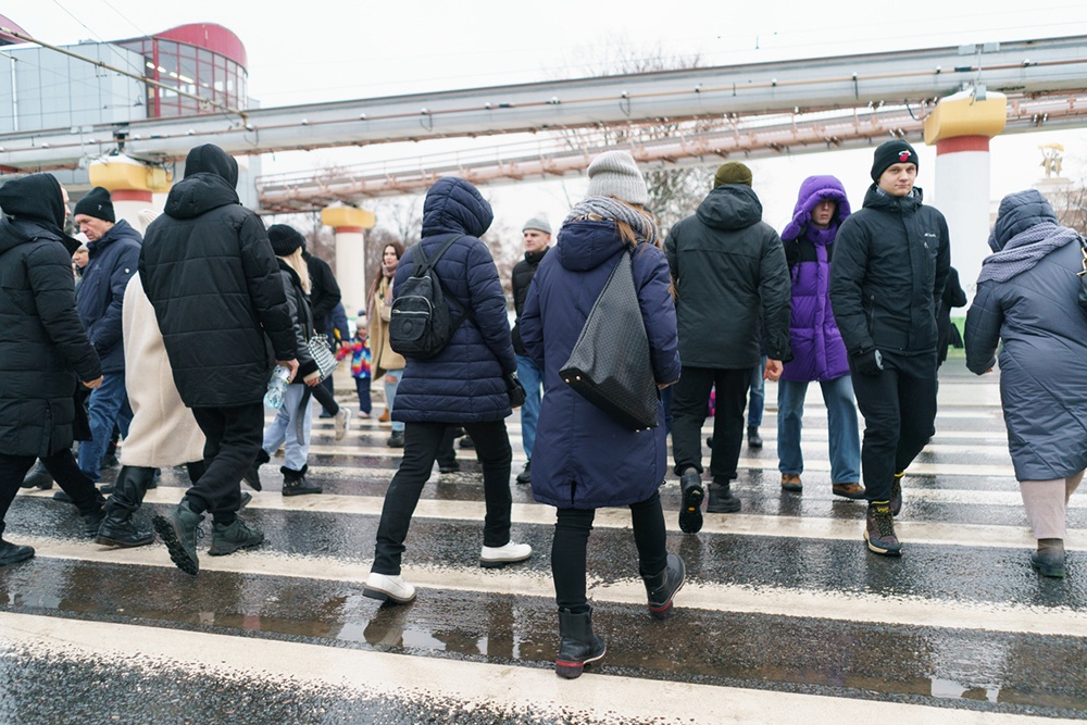Молодой человек спокойно медитирует в переполненном утреннем транспорте, символизируя самообладание и внутренний покой.