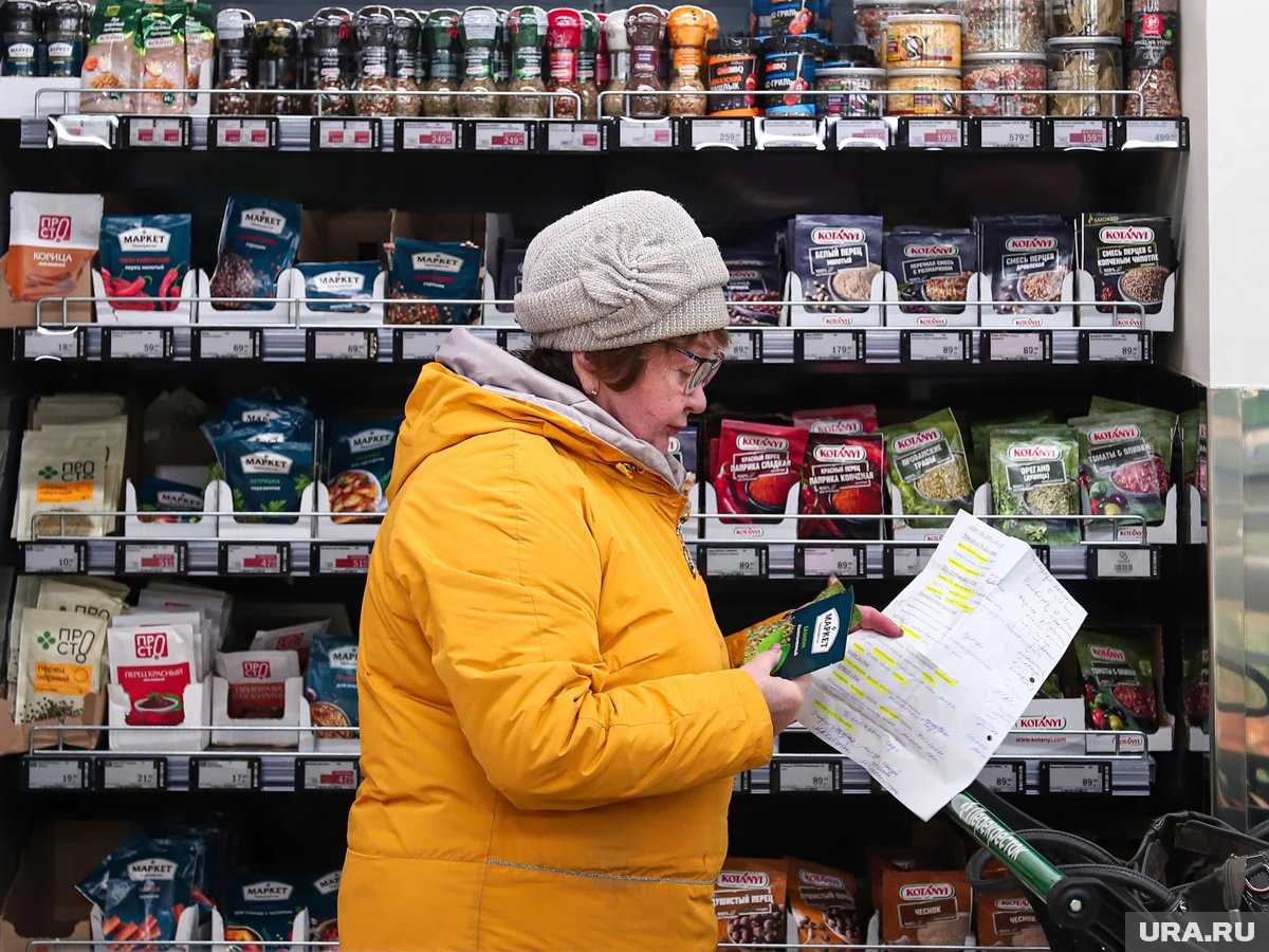 Женщина с тележкой продуктов в супермаркете, демонстрирующая умный подход к покупкам.