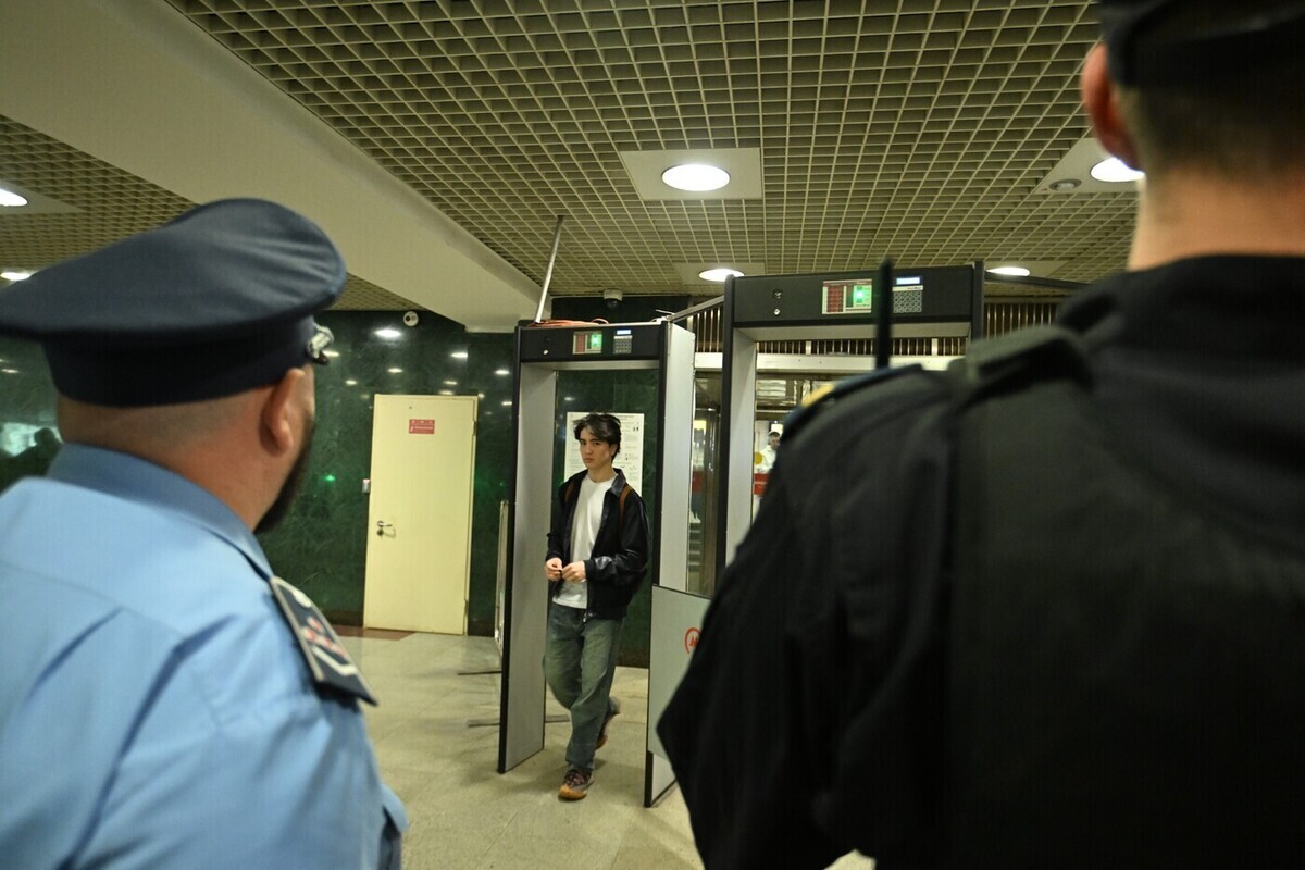 Мужчина в метро Санкт-Петербурга, сидящий на полу, возможно, под воздействием алкоголя, с книгой рядом.