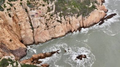 Человек пьет кофе в кофейне, расположенной на краю отвесной скалы в Китае