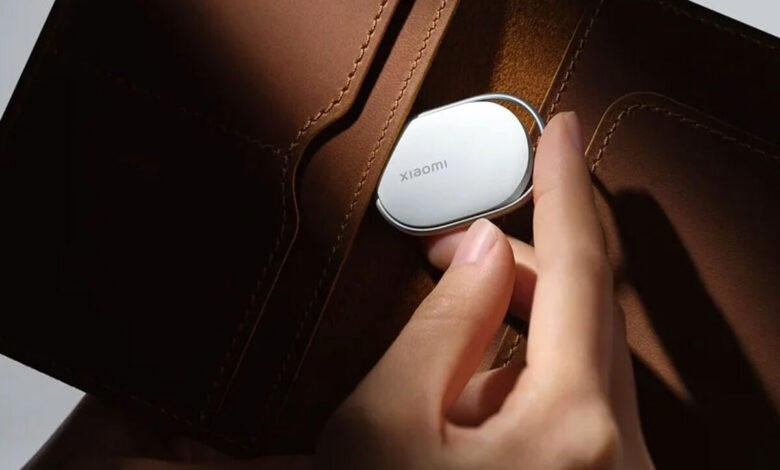 A person holding a small, sleek Xiaomi smart key finder device.