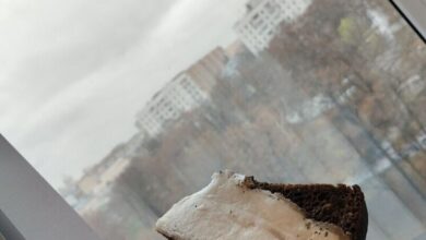 Крупный план куска сала на разделочной доске, рядом нож и специи. На заднем плане размытый интерьер кухни.