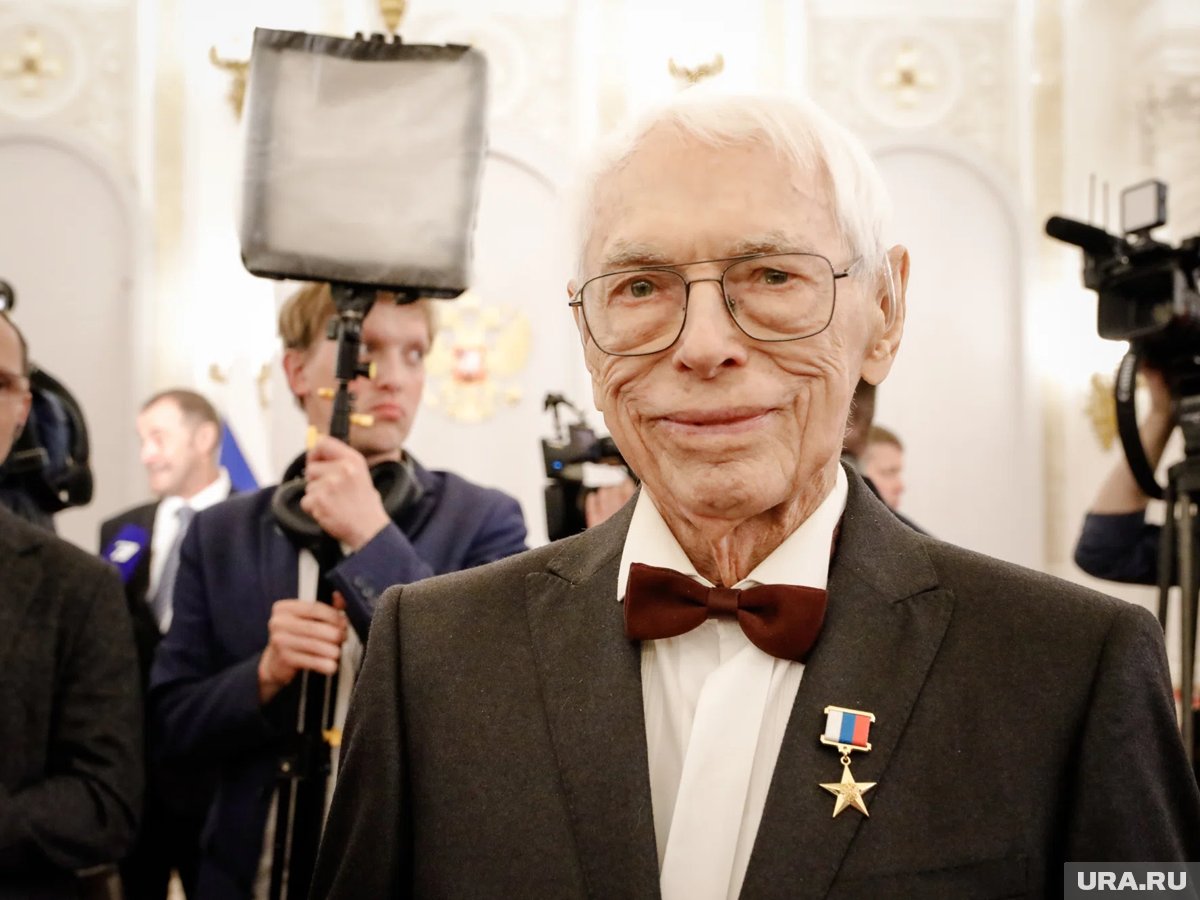 Композитор Александр Зацепин в возрасте 100 лет, излучающий бодрость и энергию, возможно, с намеком на его секрет долголетия, связанный с "зеленым зельем".