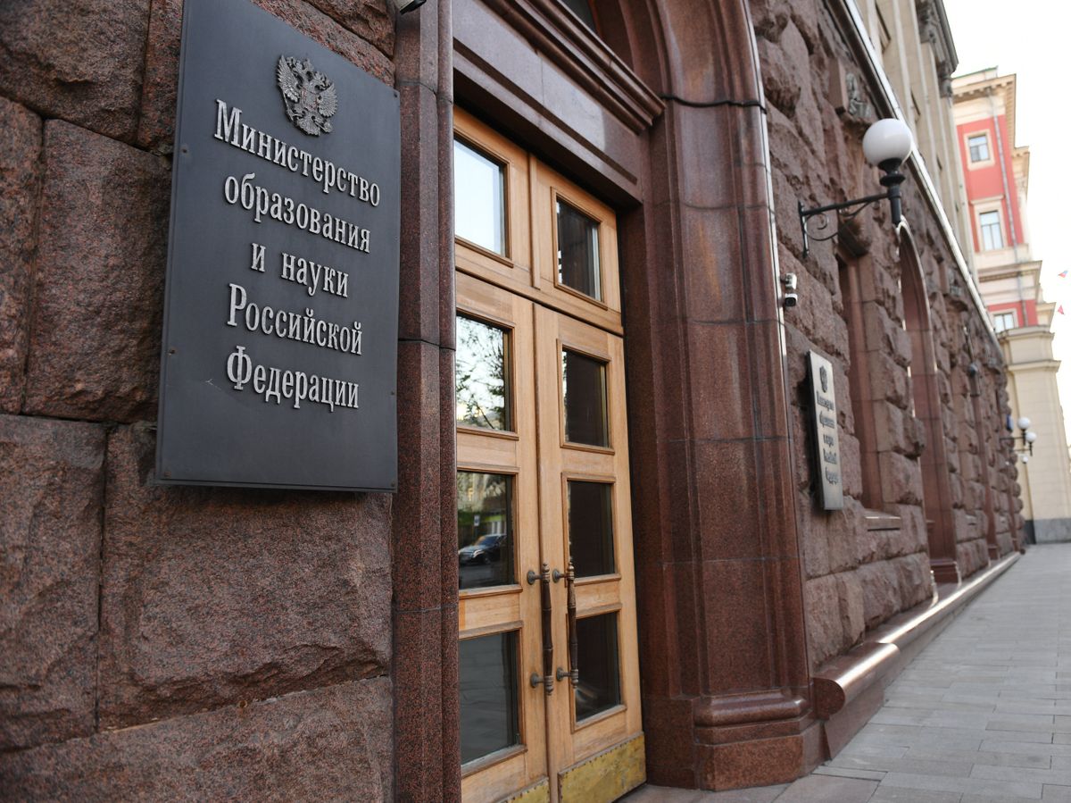 Студент стоит перед зданием университета, размышляя о жилье