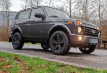 LADA Niva с табуном лошадей на фоне автосалона