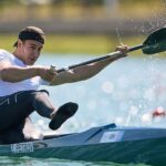 Захар Петров демонстрирует бронзовую медаль с золотым отливом на чемпионате мира по гребле