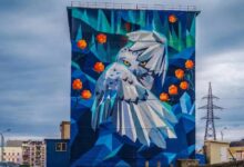 Полярная сова сидит рядом с сусликом-мечтателем на фоне северного города России