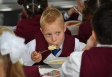 Школьная столовая, оформленная как ресторан морепродуктов, с учениками, наслаждающимися блюдами из рыбы.